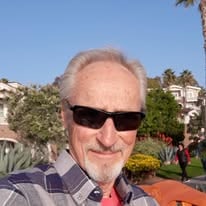 A man wearing sunglasses outdoors beneath a clear sky